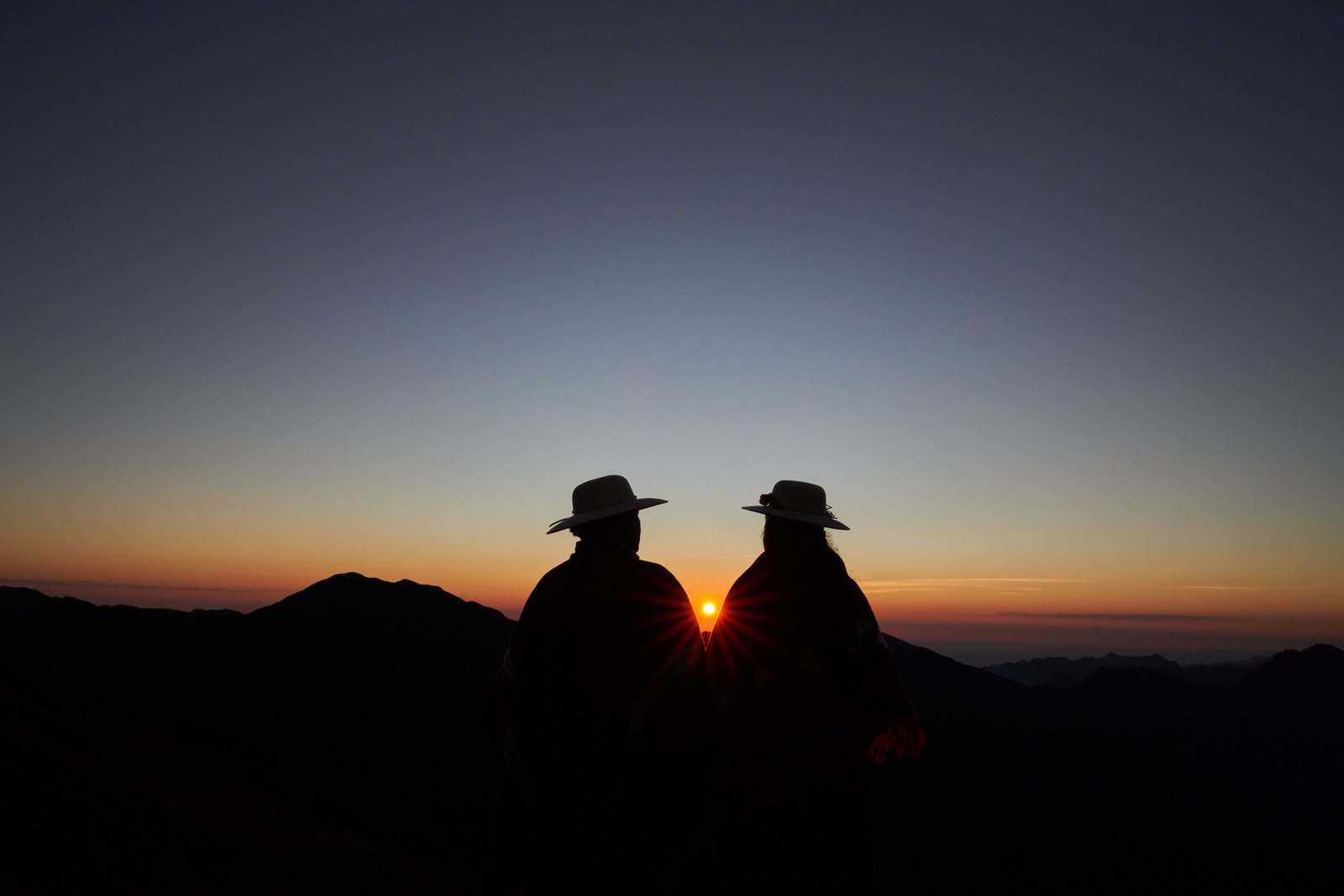Dos personas con sombrero miran el amanecer en la montaña — Geografías de la memoria, Natalia Favre, Jujuy